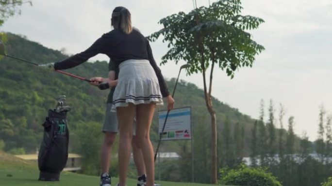 亚洲现役女高尔夫球手教男孩在高尔夫球场上打高尔夫球