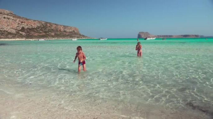 孩子们在克里特岛巴洛斯海滩的湛蓝海水中玩耍