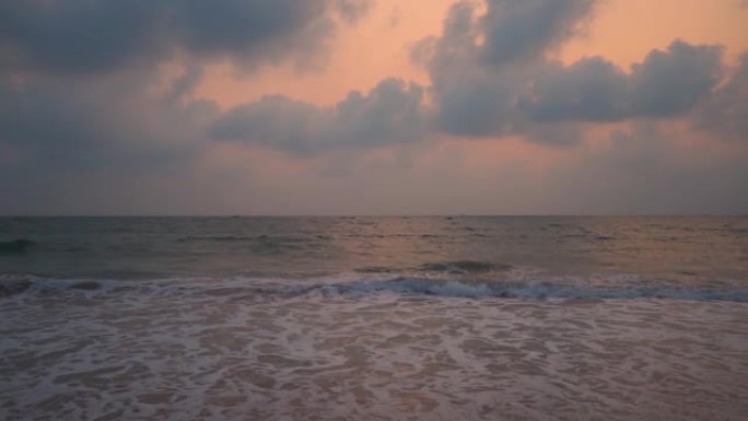 印度果阿安朱纳海滩日落时海浪的广角慢镜头。日落时海面上的云。美丽的海滩日落背景。海滩概念的暑假。