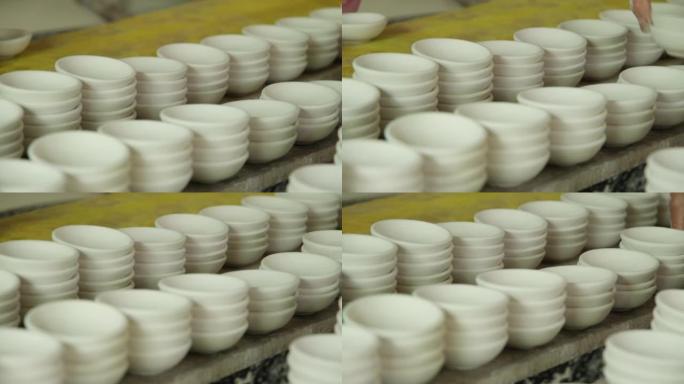 许多用陶瓷粘土制成的小圆板。机架中的陶瓷杯为陶器车间表面的绘画设计做准备。手工艺和小企业概念。