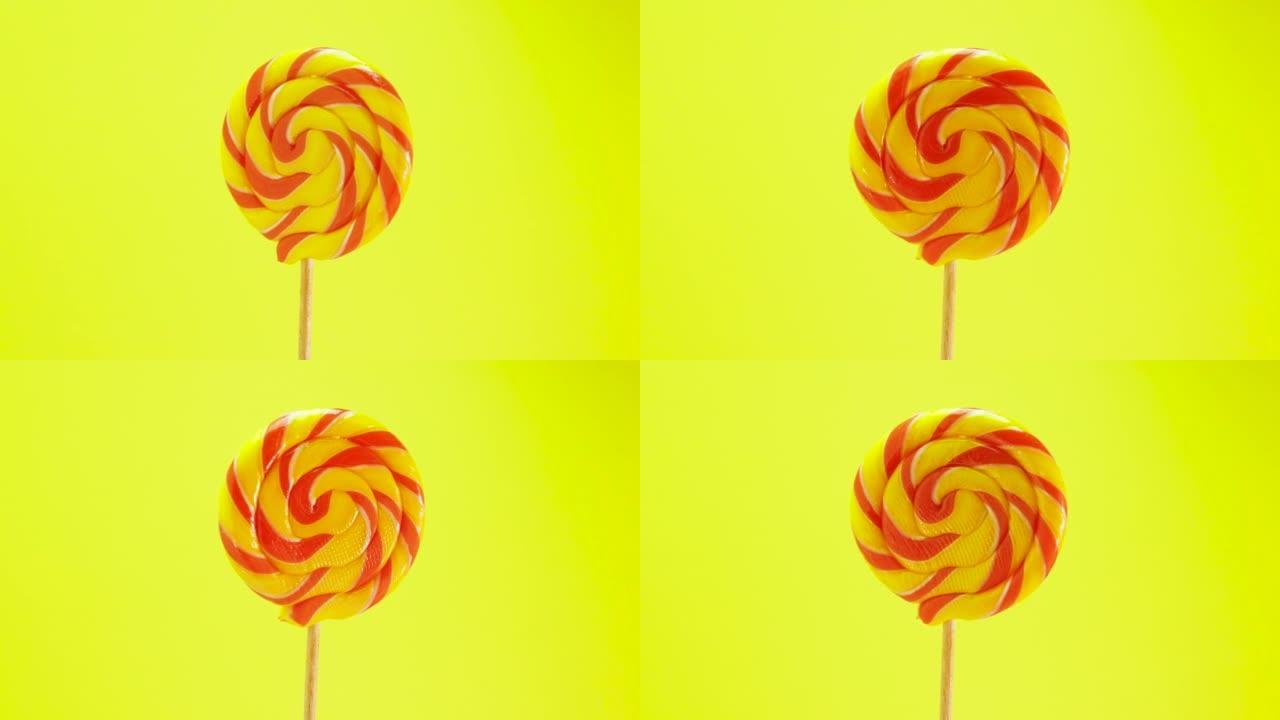 彩色棒棒糖在黄色背景上旋转。棍子上的糖果。