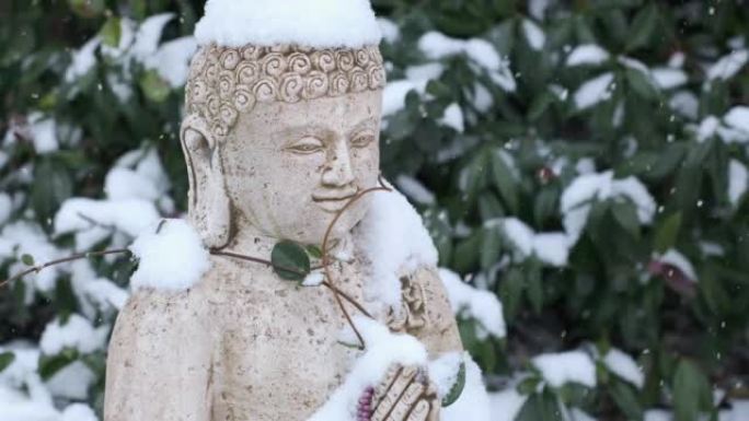 佛像石像和花园里飘落的雪。