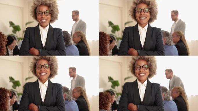 非洲女商人在与银行办公室内的同事一起工作时在镜头前微笑