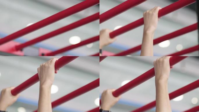 在健身房的红色拉杆上锻炼人的手的特写镜头。