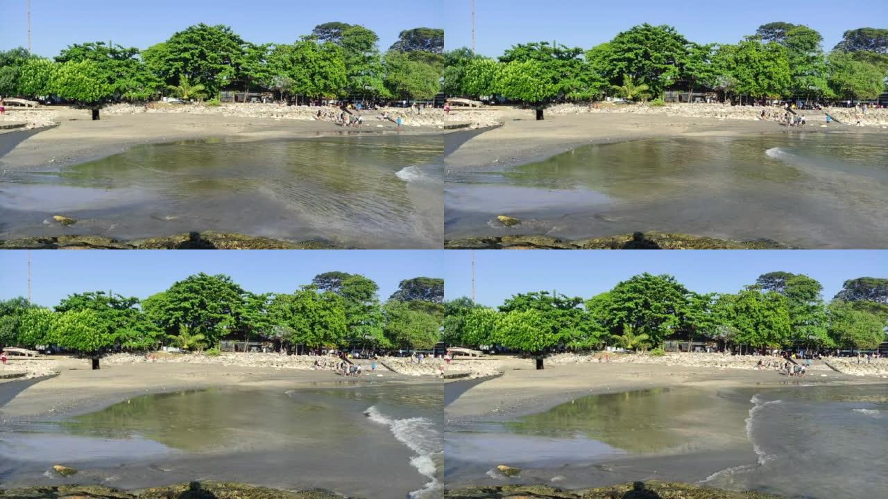 2022年5月22日印度尼西亚巴厘岛沙努尔海滩平静的海浪和郁郁葱葱的绿树