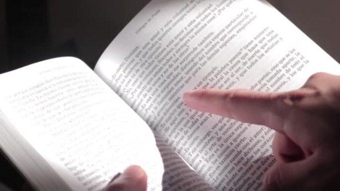 快速翻动西班牙书籍的页面，并用手指指向文字