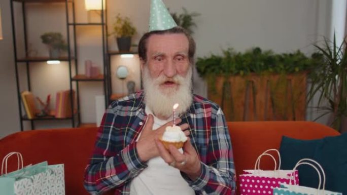 快乐的老人庆祝生日聚会，许愿在小蛋糕上吹蜡烛