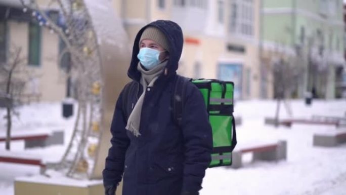 快递员在冬天背着背包送食物。