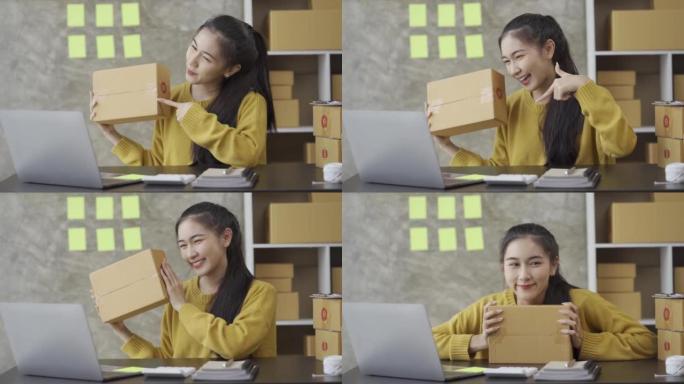 创办一个中小企业，一个独立的亚洲女性使用带盒子的笔记本电脑的小企业企业家。快乐的成功女人从事在线营销