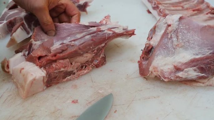 屠夫用斧头对一块生肉进行精确的打击，在砧板上切碎骨头。肉品加工厂切割店屠夫的工作过程。