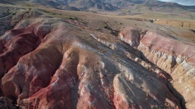 俄罗斯阿尔泰地区美丽的彩虹山脉的空中倾斜拍摄。称为火星的地质构造。由于矿物的沉积，砂岩山链被多色图案