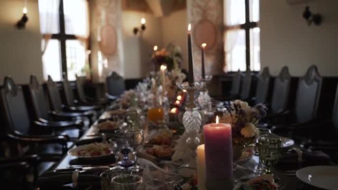 黑暗房间里漂亮的桌子布置。桌子上装饰的鲜花、蜡烛。