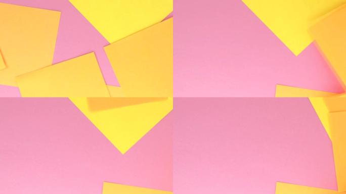 4到视频，方形的黄色便条纸在粉红色的纸背景上飞离风，俯视图