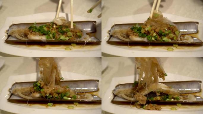 在中餐餐厅用筷子吃烤剃刀平静的玻璃面条