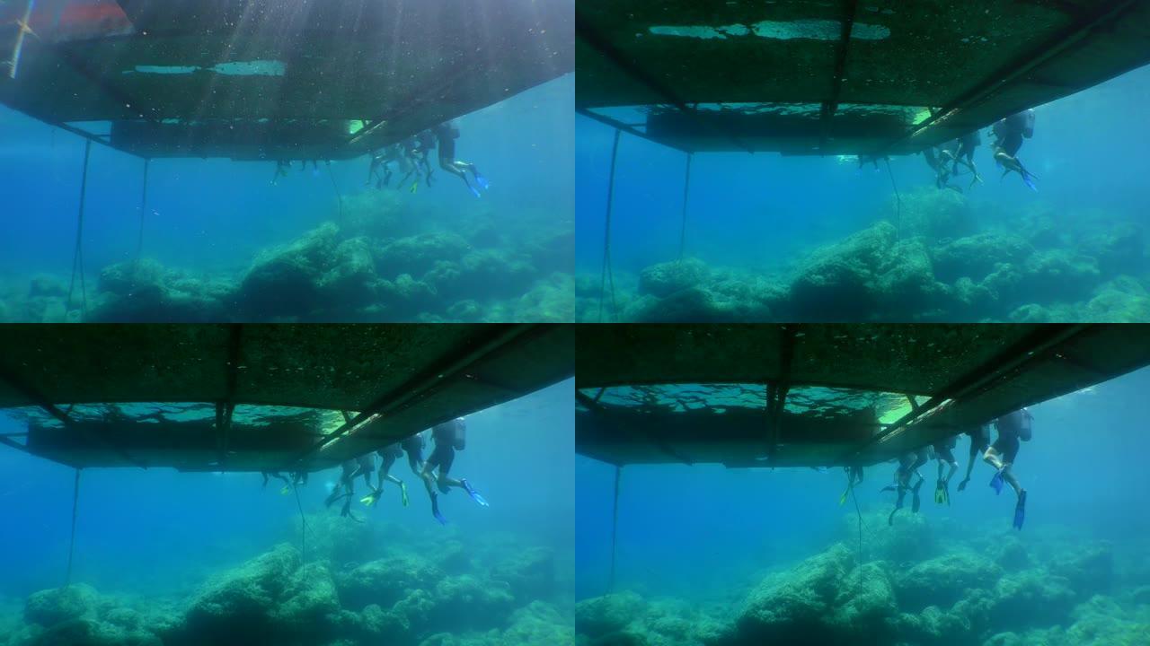 潜水训练: 一群学生潜水员在浮台边缘，仰视。