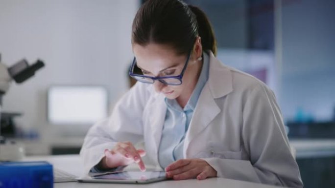 年轻的科学家在实验室里使用数字平板电脑。从事法医和医学研究的女性病理学家，同时在线分析数据和发现。研