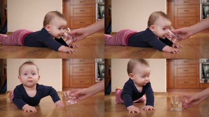 母亲给婴儿一杯水，孩子躺在家里的地板上喝