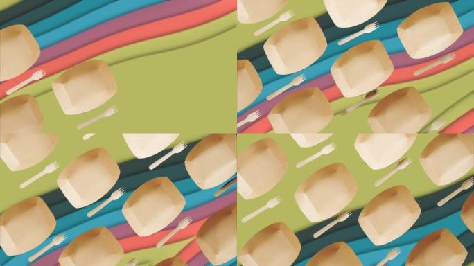 彩色抽象背景上的纸质一次性盘子和木叉。停止运动。可生物降解材料。一次性餐具