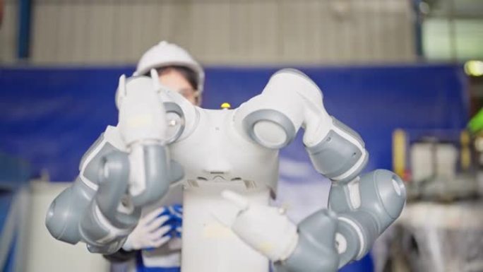 年轻女服务工程师手持机器人控制器操作机器人手臂自动化工厂
