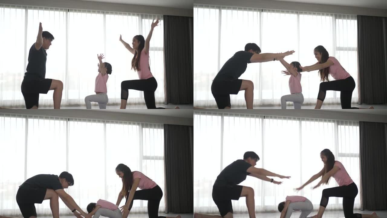 父亲和母亲正在家里和女儿一起锻炼。