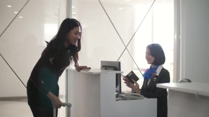 微笑的女航空公司工作人员在机场的值机柜台为旅客提供服务