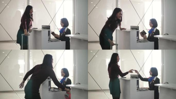 微笑的女航空公司工作人员在机场的值机柜台为旅客提供服务