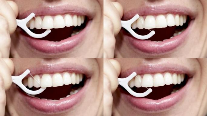 关闭4 k视频女人的嘴微笑和用白色塑料牙签用牙线洁牙。美丽性感的微笑，嘴唇。天然牙齿。牙科保健概念。