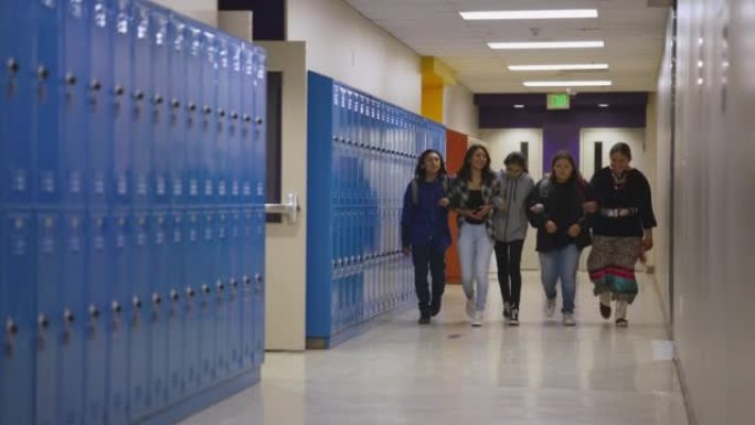 一群初中和高中孩子隔着双臂穿过学校走廊