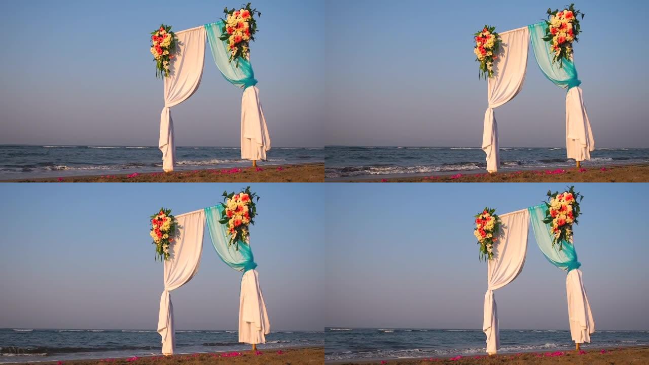 户外美丽的夏季婚礼。海上用浅色布和白色和粉红色花朵制成的婚礼拱门