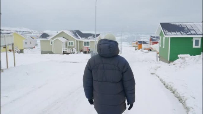 穿着冬装的男人走过Ilulissat的白雪覆盖的街道