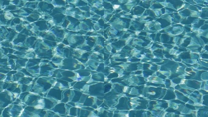 阳光照射的游泳池的绿松石表面。抽象反射和折射光