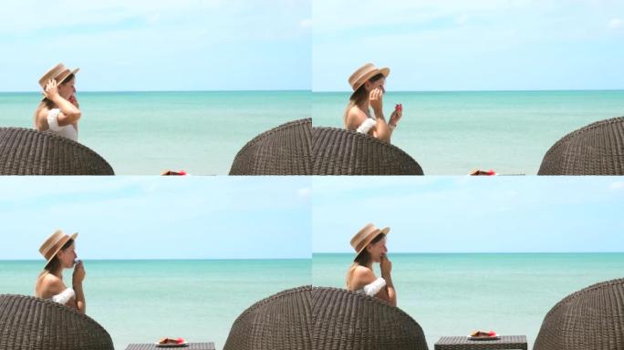戴着草帽的迷人年轻女子坐在海边的海滩咖啡馆里，吃西瓜