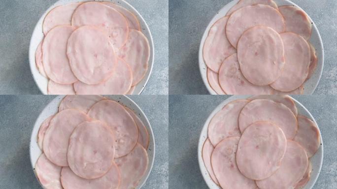 猪肉火腿薄片放在盘子上旋转。将碳酸盐切成薄片的肉放在盘子里