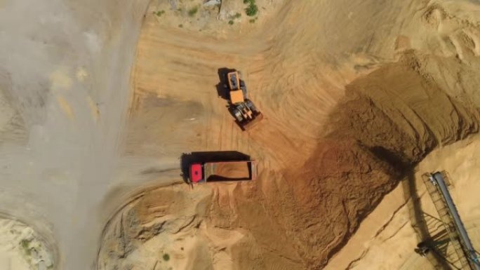 在采石场将碎石砂装载到卡车中的挖掘机的俯视图