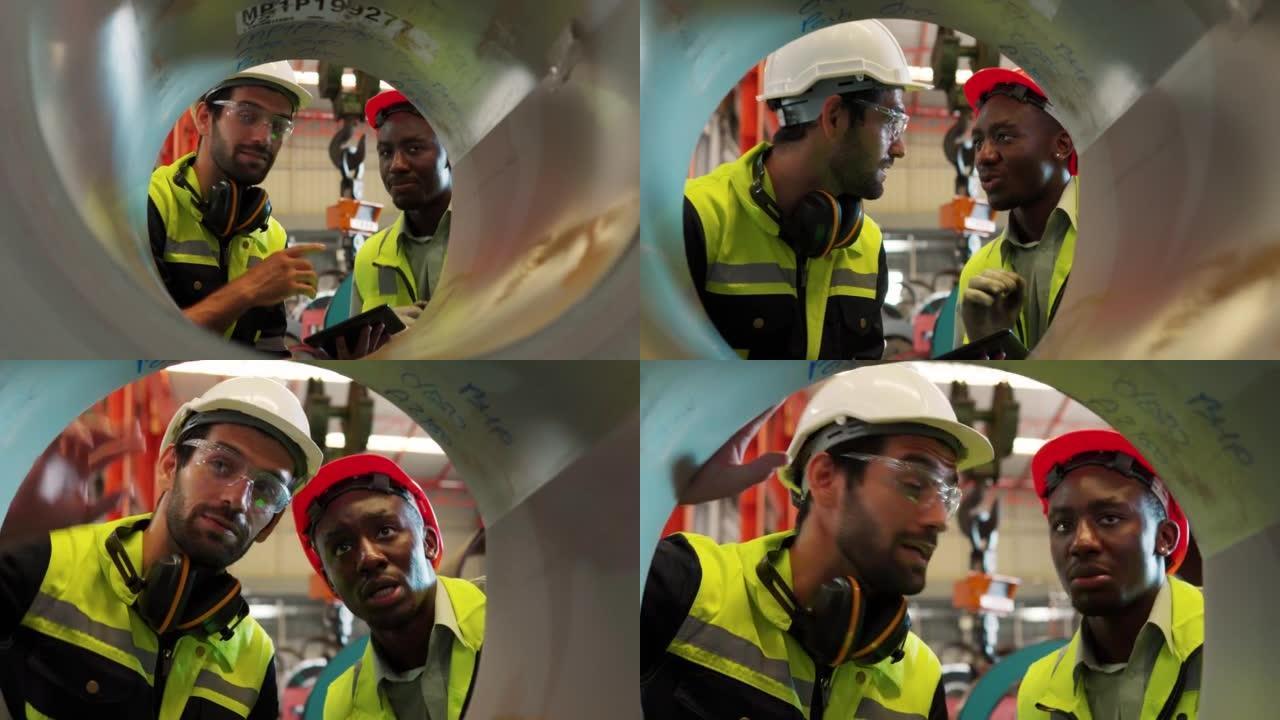 两名工程师工人穿着制服，戴着安全安全帽，在工业施工现场检查金属片卷。
