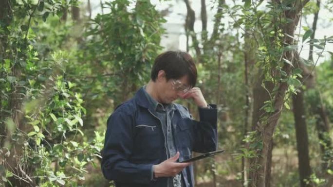 戴着防护眼镜、穿着工作服的一名男子正在拿着平板电脑进行环境调查。