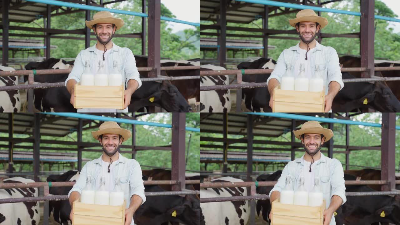 高加索男性奶农的肖像在牛棚里拿着一瓶牛奶。年轻英俊的男性农业农民微笑着看着相机在畜牧业用幸福挤奶后