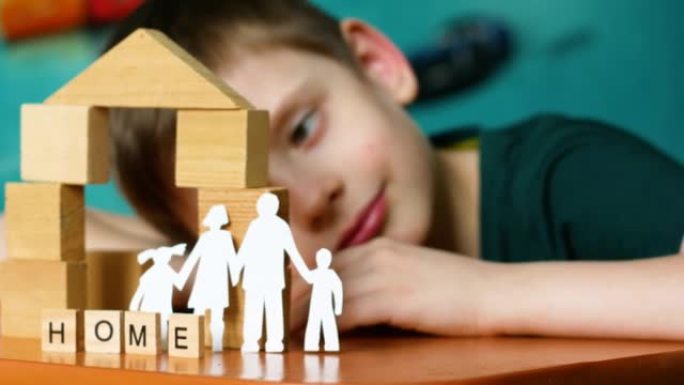 纸雕家庭，用立方体制成的房子，题词家庭游戏和一个高加索学龄前儿童的梦想。一个可爱的孩子玩立方体的肖像