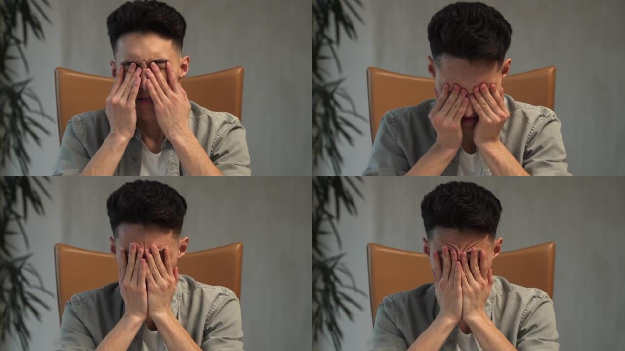 疲惫的亚洲男子下班后关闭笔记本电脑揉眼睛