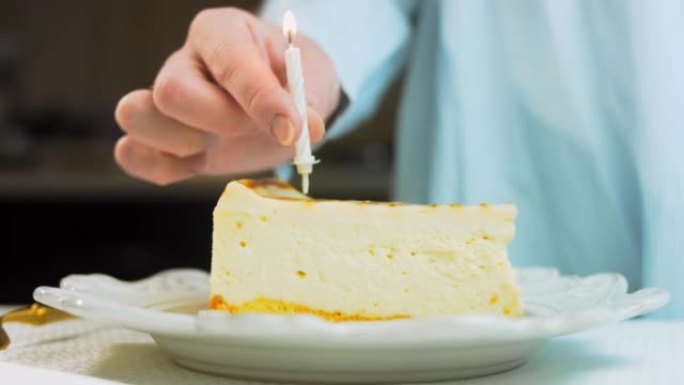 复古盘子上的焦糖芝士蛋糕。使用金叉和小刀。女人把点燃的蜡烛放在蛋糕上。我们庆祝生日