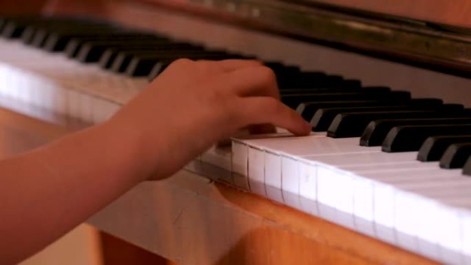 手指年轻钢琴家的右手在钢琴的白色琴键上演奏练习，音乐教育