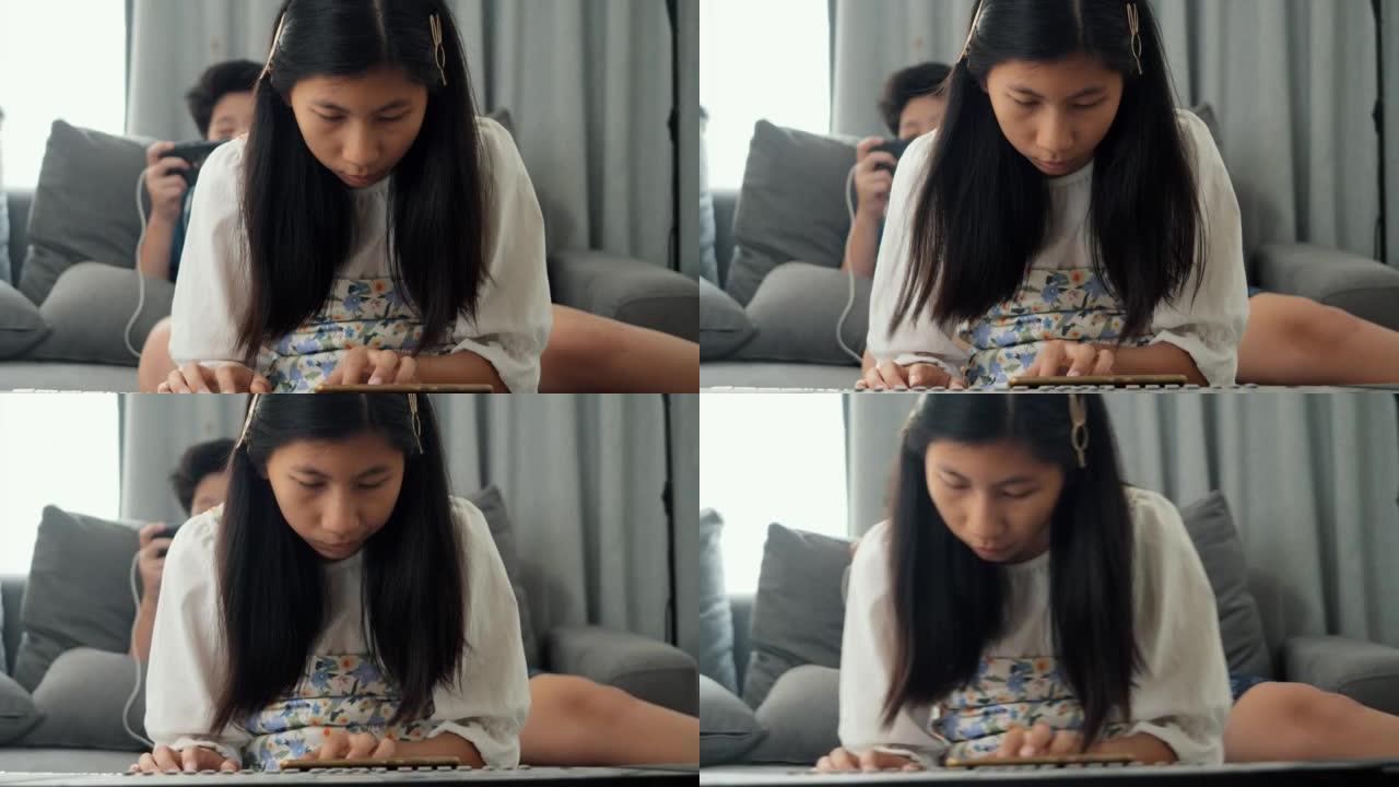 亚洲女孩在家里玩手机游戏的哥哥附近的沙发上通过手机应用学习玩键盘乐器，生活方式概念。