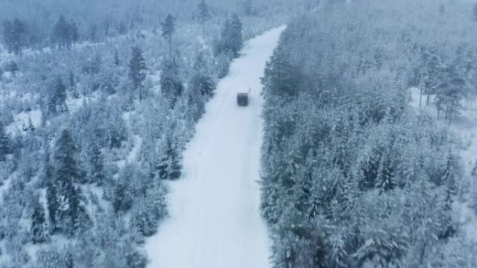 瑞典北部积雪覆盖的山区景观降雪期间，小型卡车在冬季森林路上行驶后的空中射击