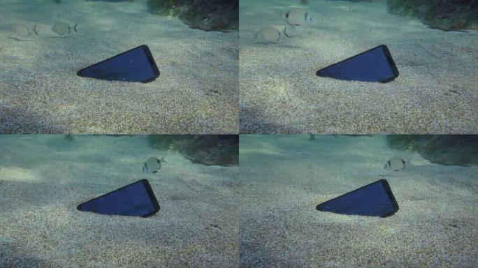 丢失智能手机在沙底，在背景鲷鱼。