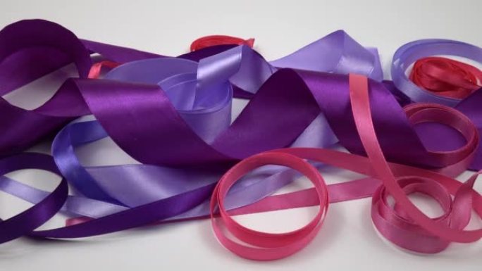 缎面紫色和粉红色丝带躺在白色背景上