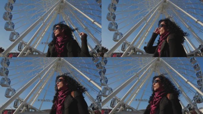 迷人的时尚黑发女孩，一个戴着高德太阳镜的卷曲非洲头发的女人，在阳光明媚的日子站在城市广场上。在白色摩