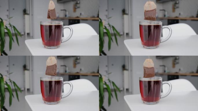 一整杯茶的茶包。茶袋金字塔从杯子中慢慢移开，一股细细的茶流。
