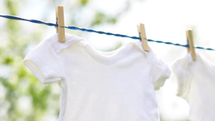 春季户外挂在绳子上的白色婴儿衣服
