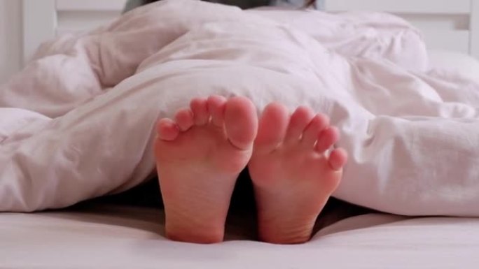 女人在床上嬉戏地摇着脚和手