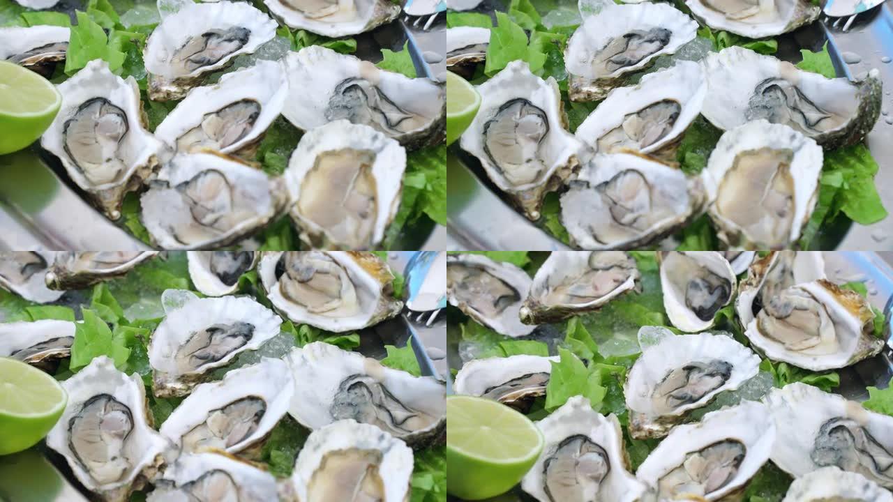 在托盘上打开新鲜牡蛎，配以冰和酸橙片，地中海美食海鲜，海鲜餐厅的皇家软体动物